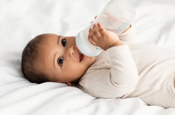 Søt, liten afroamerikansk baby som drikker av flaske – stockfoto