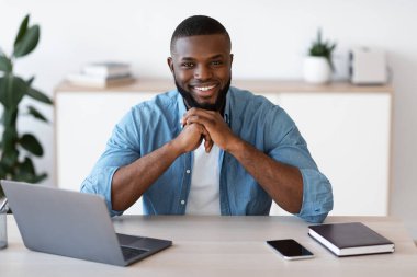 İç işlerindeki masada oturan gülümseyen Afrikalı Amerikalı girişimcinin portresi