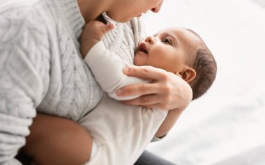 Genç bir kadın küçük, tatlı bir Afrikalı Amerikalı bebeği elinde tutuyor.