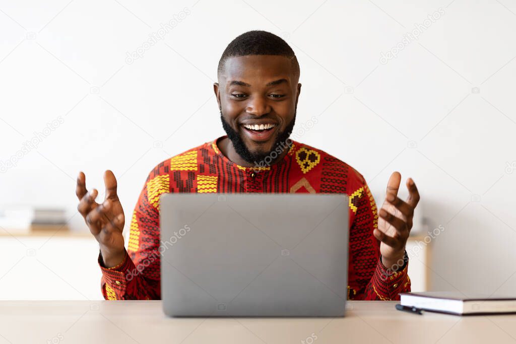 Online Communication. African Guy In Traditional Shirt Having Video Call On Laptop