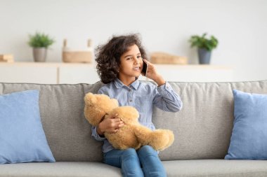 Gülümseyen siyah kız cep telefonuyla konuşuyor.