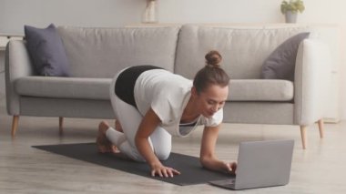Çevrimiçi fitness eğitimi. Genç bir kadın koçunu selamlıyor ve kalas egzersizine başlıyor.