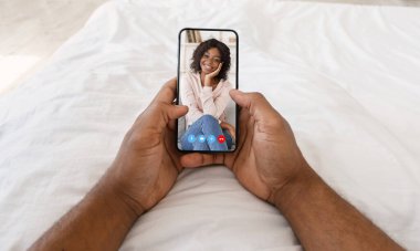 Tanımlanamayan bir adam akıllı telefondan kız arkadaşıyla konuşuyor, evde yatağında video görüşmesi yapıyor.