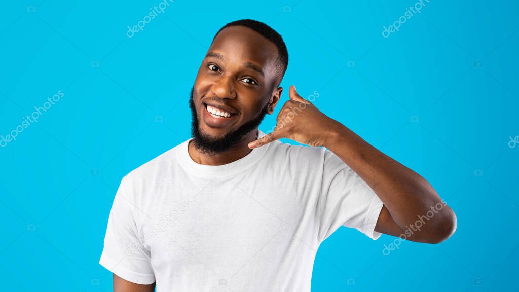 African Guy Showing Call Me Gesture Standing Over Blue Background