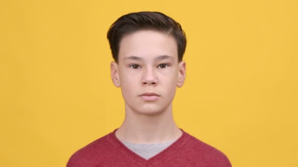 Porträt eines ernsthaften Teenagers, der vor gelbem Hintergrund posiert — Stockvideo