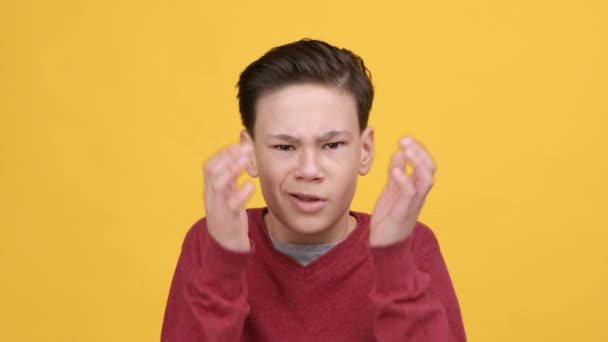 Adolescente menino encolhendo ombros balançando cabeça em desacordo, fundo amarelo — Vídeo de Stock