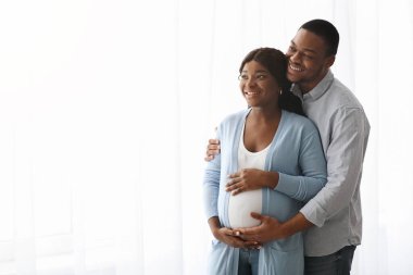 Neşeli Afrikalı Amerikalı hamile çift fotokopi odasına bakıyor.