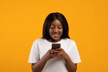 Neşeli Afrikalı Amerikalı kadın cep telefonu kullanıyor.