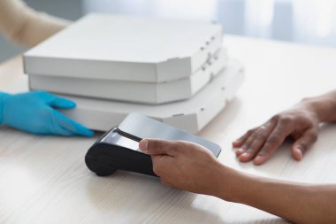 Milenyum Afrikalı Amerikalı adam terminalde boş ekranlı akıllı telefonla ödeme yapıyor.