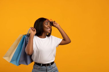Güneş gözlüklü ve alışveriş çantalı neşeli siyahi kadın.
