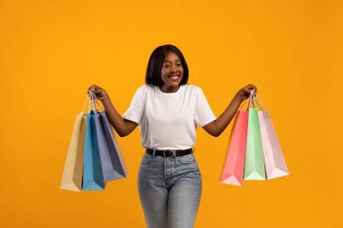 Duygusal siyahi kadın alışveriş torbalarıyla el kaldırıyor.