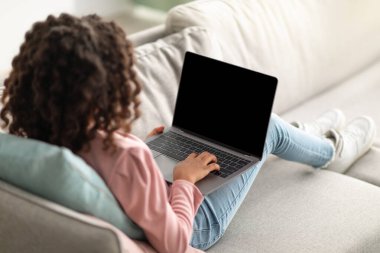 Genç bir kızın dizüstü bilgisayara boş ekranla baktığı, öğretmeniyle veya öğretmeniyle video görüşmesi yaptığı, salgın sırasında internetten ders çalıştığı bir fotoğraf.