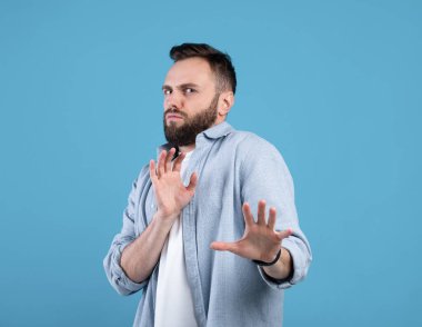 Milenyum adamı bir şeyi reddediyor, mavi stüdyo arka planında duraksama hareketi yapıyor.