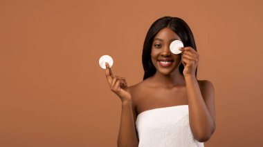 Bir gözünü pamukla kaplayan neşeli siyah kadın.