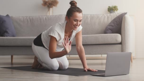 Sport träning hemma. Ung fitness coach hälsar sina studenter och börja träna, visar planka motion till bärbar dator — Stockvideo