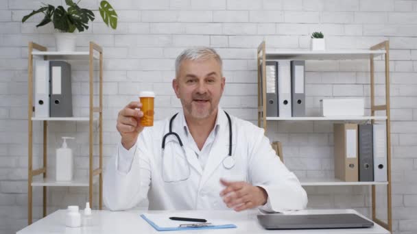 Mature Doctor Showing Tube With Medical Pills Sitting In Office — Stock Video