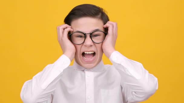 Loco colegial gritando enojado tocando la cabeza sobre fondo amarillo — Vídeo de stock