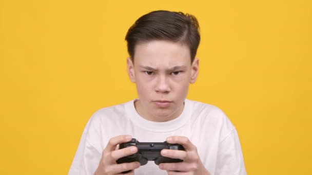 Ragazzo adolescente che gioca a videogame con controller Gamepad su sfondo giallo — Video Stock