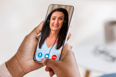 Çevrimiçi Öğretmenlik. Tanımlanamayan siyah kadın özel hocasıyla video görüşmesi için akıllı telefon kullanıyor.