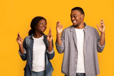 Dilek tutuyorum. Neşeli Afrikalı Amerikalı çift şans için dua ediyor.