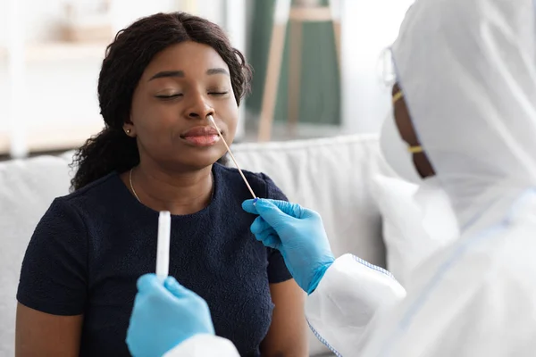 Doctor in protective suit takes swab to patient at home — Stock Photo, Image