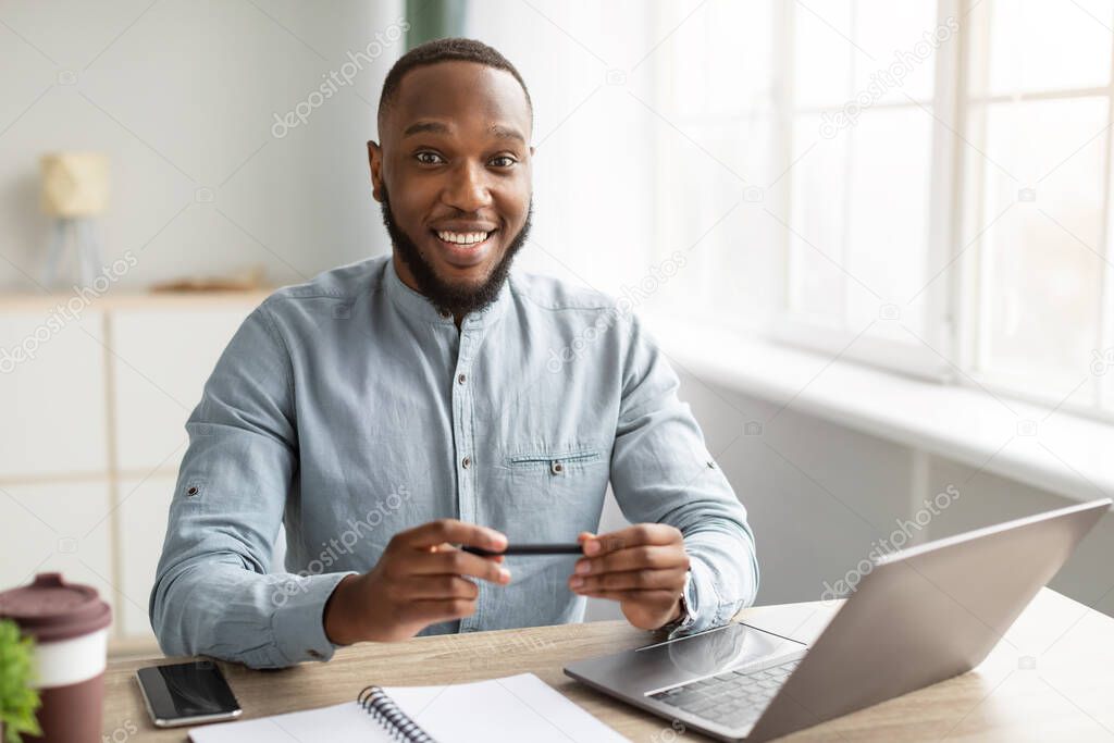 Portrait Of Happy Black Businessman Sitting At Workplace In Office