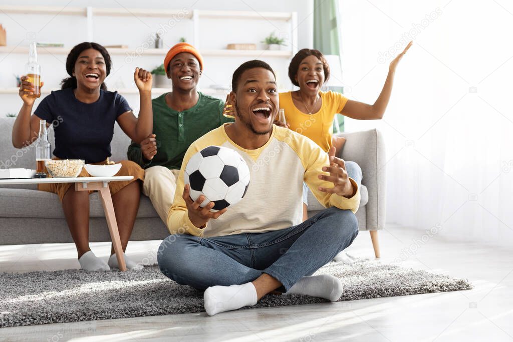 Emotional african american friends watching football game at home