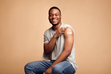 Covid-19 Aşılanmış Afrikalı Adam Kolunu Alçılı gösteriyor, Bej Arkaplan