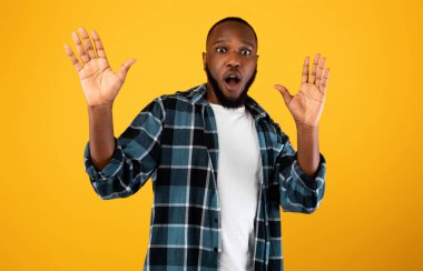 Shocked African American Guy Raising Hands Posing Over Yellow Background