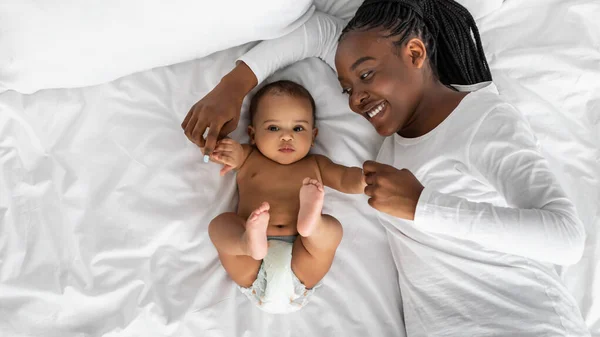 African American mom lying in bed with her cute infant — Stock Photo, Image