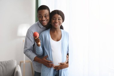 Beautiful african american pregnant couple with fresh apple