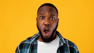 Shocked African Guy Looking At Camera Posing On Yellow Background