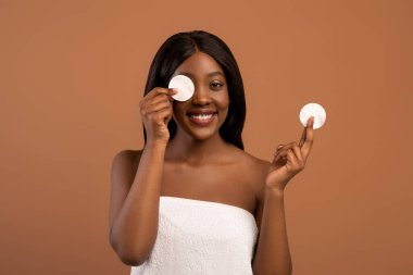 Afrikalı Amerikalı kadın duştan sonra tonerle yüzünü temizliyor.