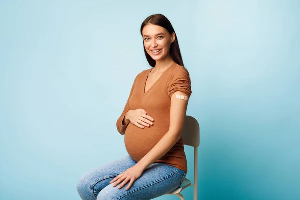 Pregnant Lady Showing Vaccinated Arm After Coronavirus Vaccination, Blue Background