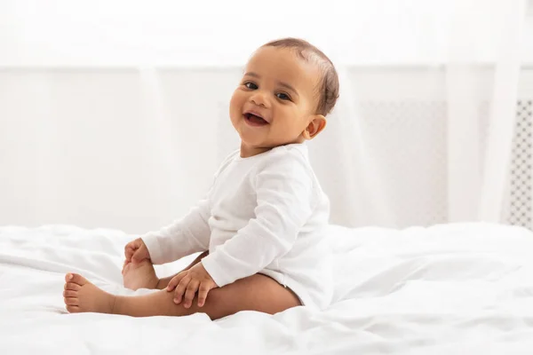 Retrato de bebê africano criança sorrindo sentado na cama interior — Fotografia de Stock