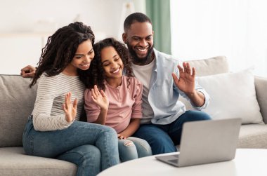 Siyah ailenin dizüstü bilgisayarla el sallayarak video görüşmesi yapması