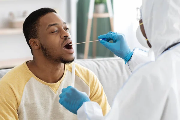 Doc in protective suit takes swab from throat