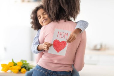 Sevimli siyah kız annesini lalelerle ve kartlarla selamlıyor.