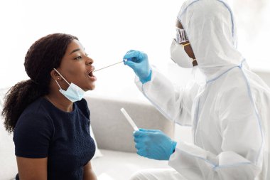 Koruyucu giysili hemşire hastadan örnek alıyor.