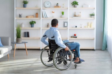Engelli yetişkinlerde depresyon. Tekerlekli sandalyedeki mutsuz siyah adam kendini evde yalnız hissediyor.