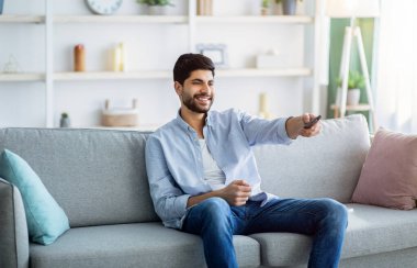 Televizyon izliyordum. Mutlu Arap adam dinleniyor, uzaktan kumandayla kanal değiştiriyor.