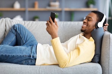 Neşeli Afrikalı Amerikalı adam cep telefonundan video izliyor.