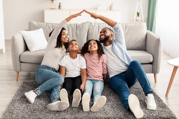 Black parents making symbolic roof of hands above children