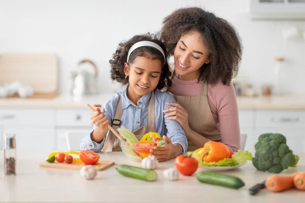 Black mother and daughter cooking tasty salad