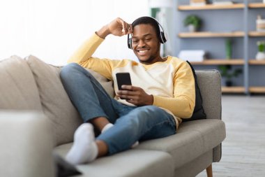 Mutlu siyah adam cep telefonundan video izliyor.