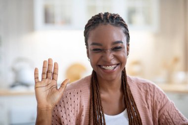 Kameraya el sallayan, video çağrısı yapan neşeli siyahi kadının yakın çekimi.