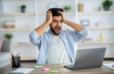 Son teslim tarihi stresi. Şaşırmış Arap adam dizüstü bilgisayara bakıyor ve kafasına dokunuyor, iş sorunları yaşıyor.