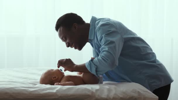 Permiso de paternidad. Joven feliz afroamericano padre dando más pequeño al bebé recién nacido y llevándolo de la cama — Vídeos de Stock