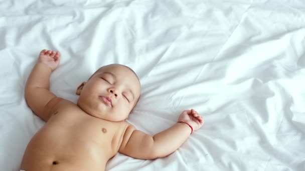 白いベッドの上で深く眠っている愛らしい面白いアフリカ系アメリカ人の赤ん坊の肖像画を閉じます,空のスペース — ストック動画