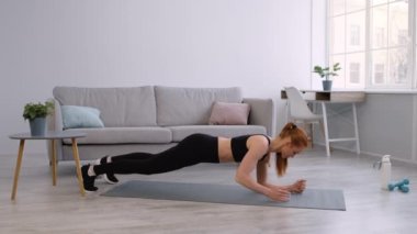 Kadın evde yumruk yumruğa geçişle Plank egzersizi yapıyor.